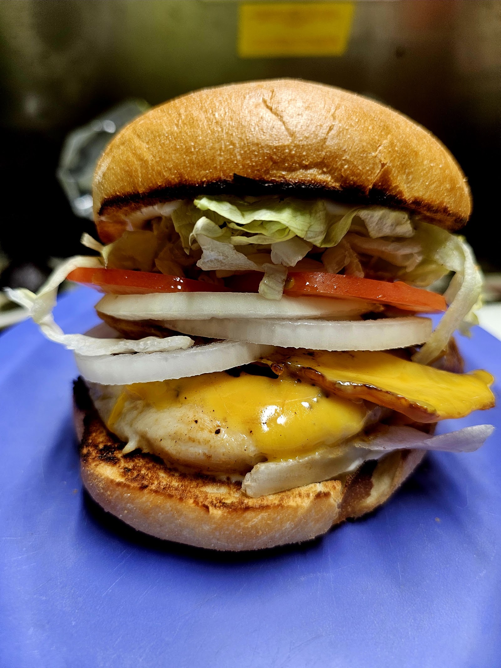 Grilled chicken burger with melted cheese, lettuce, tomato, and onion